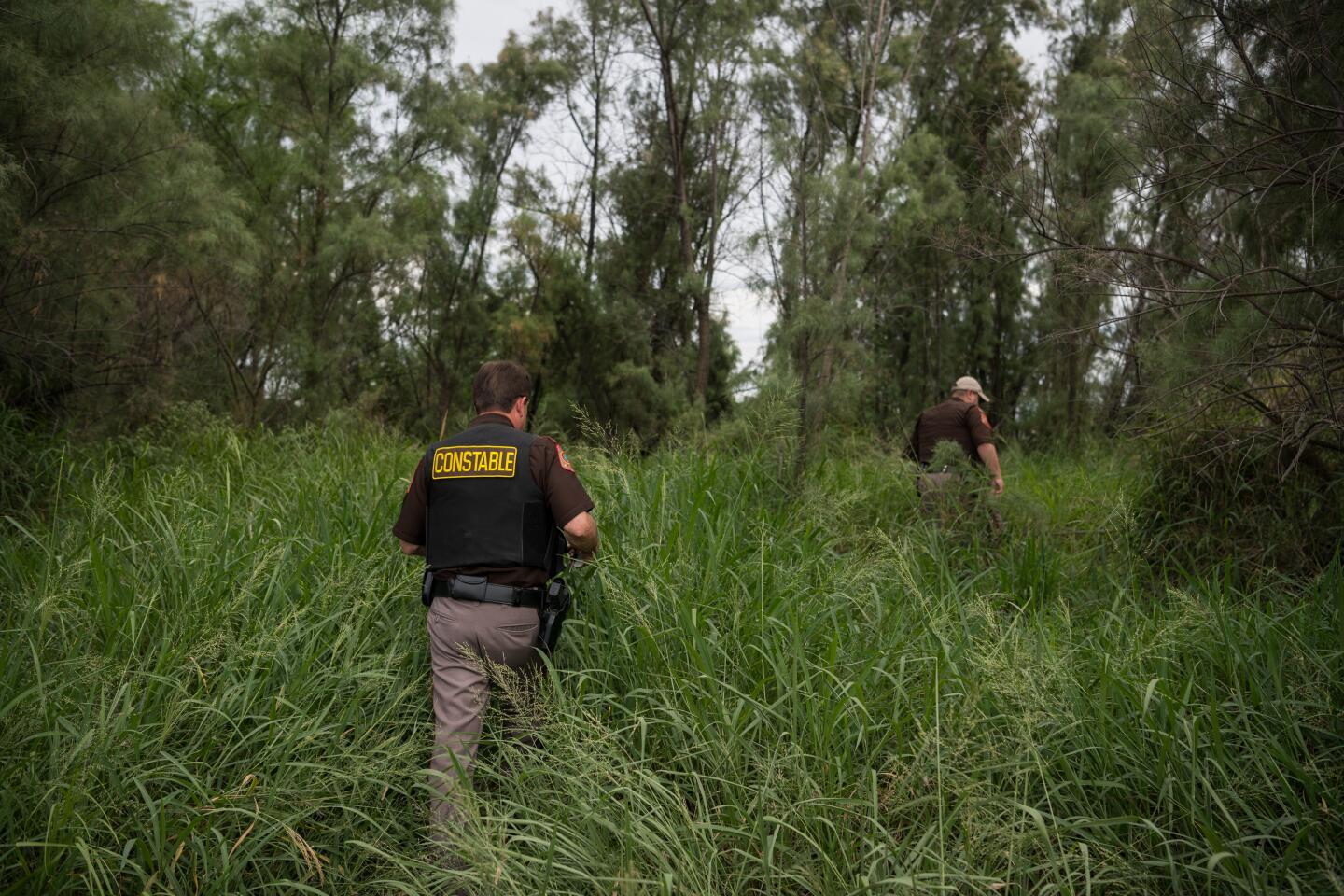Chief Deputy Rene Gonzalez (L) and Deputy Rey Reyna of the Hidalgo County Constable Precinct 3 Department walk a path to the Rio Grande at a migrant crossing Tuesday, July 23, 2019 near Mission, Texas.
