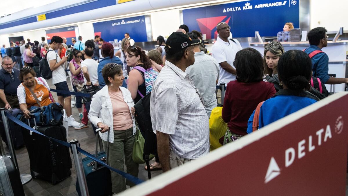 Travelers wait in line at the Delta Air Lines check-in counter at LaGuardia Airport on Aug. 8, 2016, after flights were grounded and delayed by a system outage. Delta and American Airlines have agreed to fly each other's passengers during emergencies.