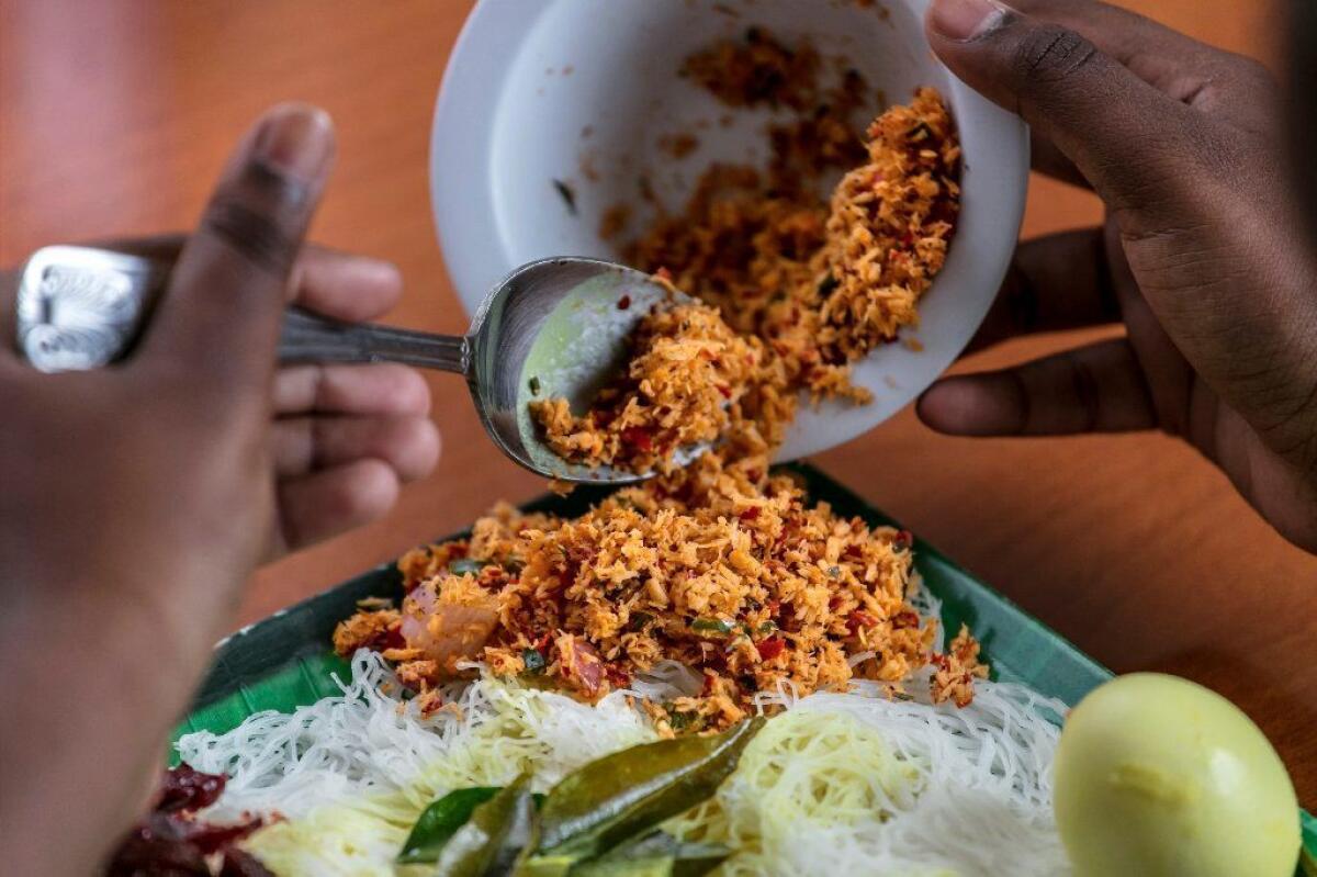 Finishing a string hopper plate with a garnish of pol sambol.