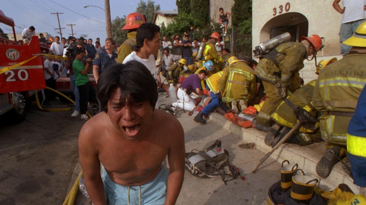Un hombre llora luego de haber pasado a un lado del cuerpo de un niño, víctima del incendio en los apartamentos de Wastlake en 1993.