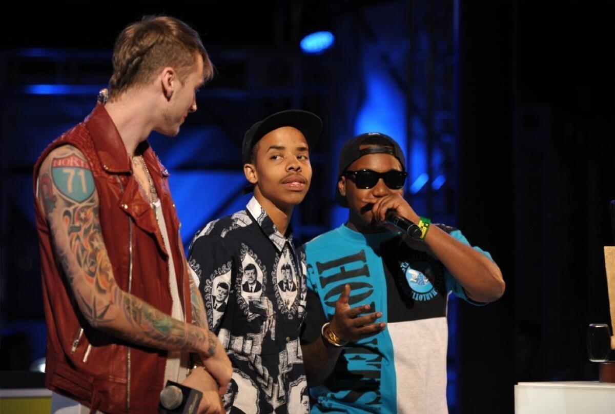 Host Machine Gun Kelly, left, presents the Breaking Woodie to Earl Sweatshirt, center, on stage at the mtvU Woodie Awards on Thursday, March 14, 2013, in Austin, Texas. Speaking at right is Domo Genesis.