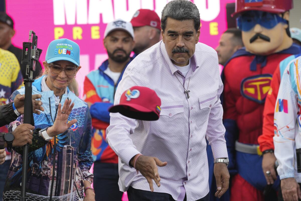  Nicolas Maduro throws a cap to supporters.