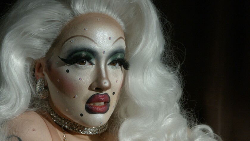 A portrait of a drag queen with long, curly white hair