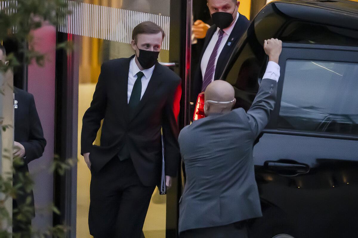 Men in dark suits near a large black SUV