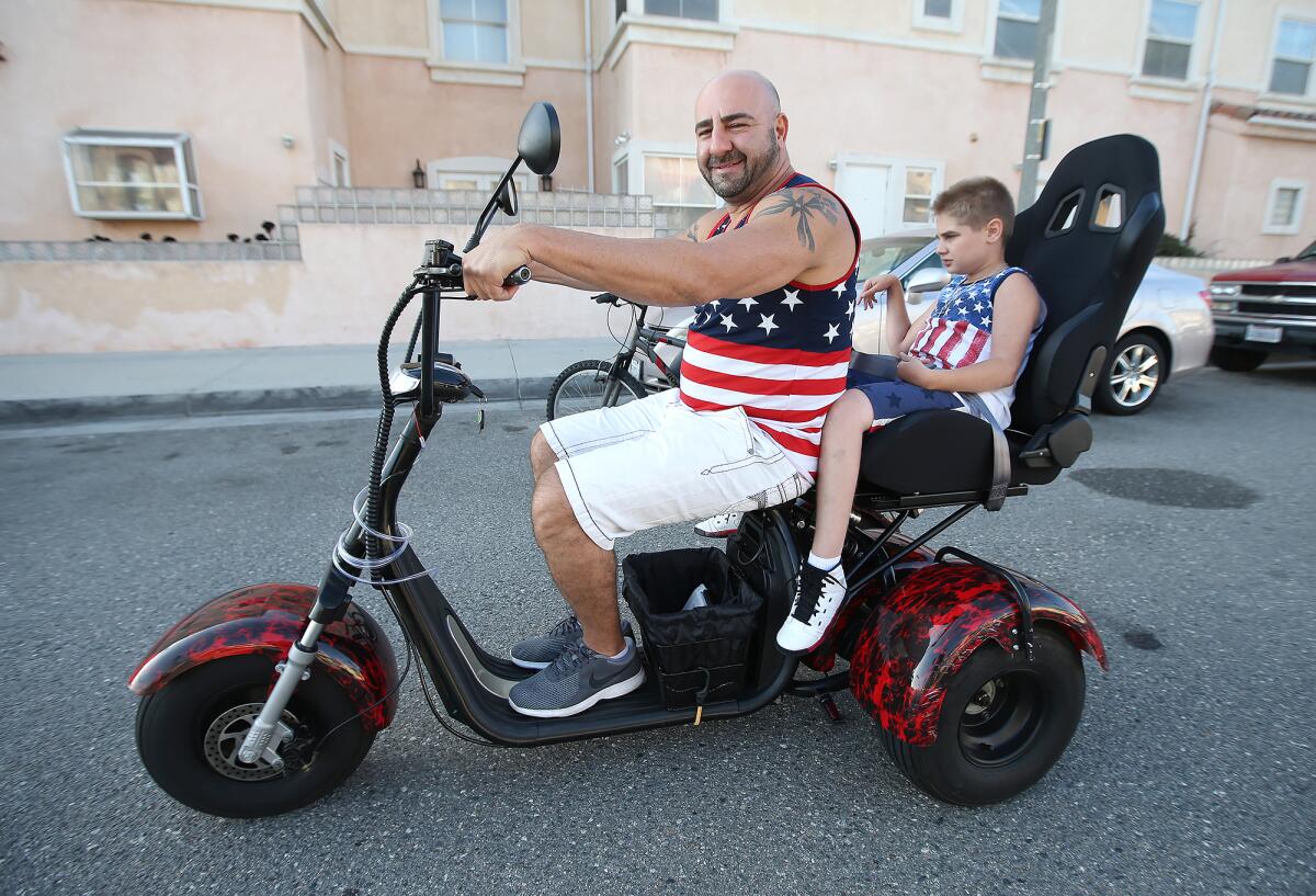Jason David and his son, Jayden, 13, take a ride to Newport Beach on a new three-wheeled motorized scooter they received as a gift from the Newport and Huntington Beach police officers associations. Jayden has a severe form of epilepsy, and the family moved from Modesto because the ocean air helps Jayden's condition.