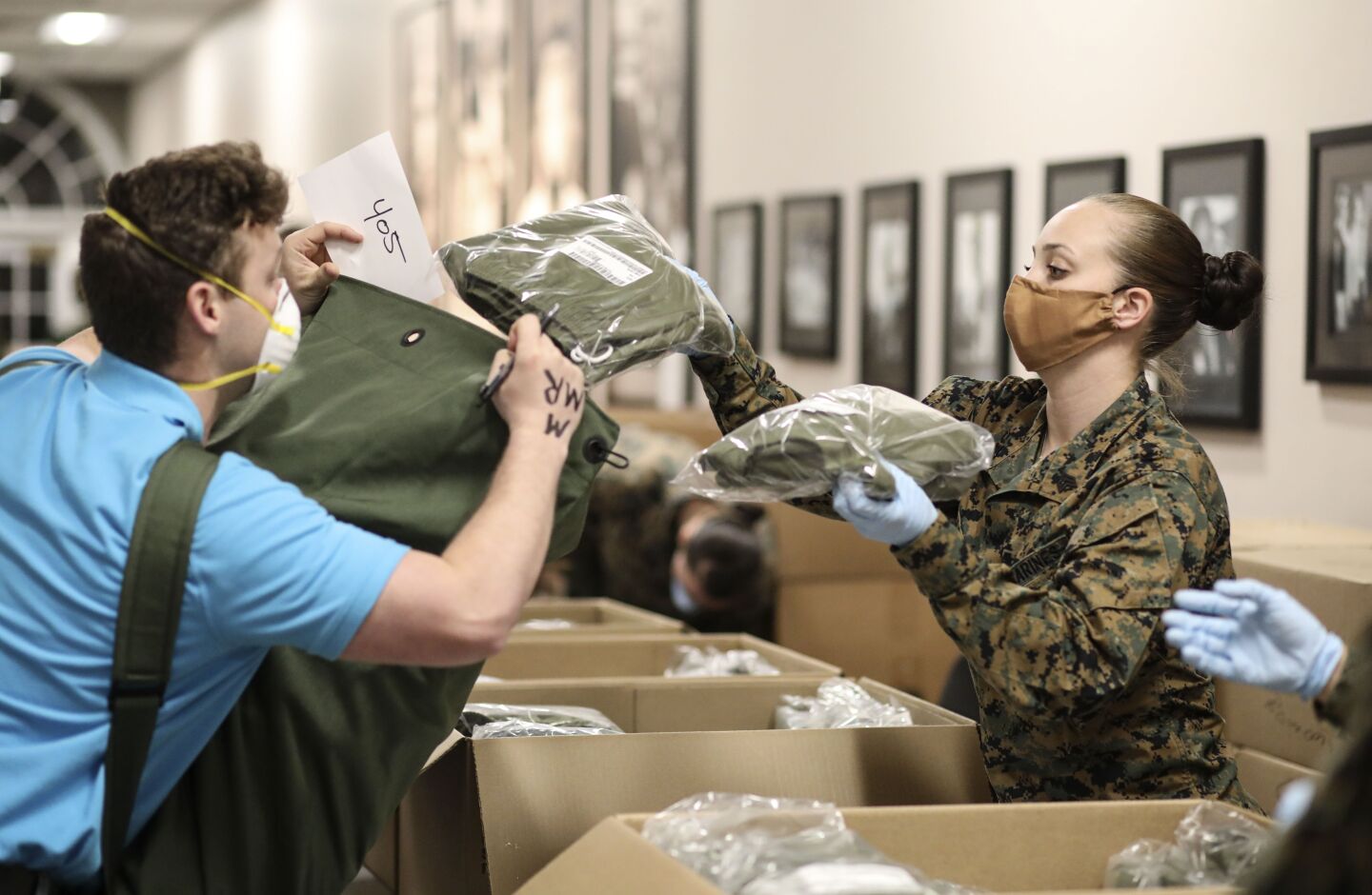 Sgt. Briana Lomeli hands a recruit clothing items at the Marine Corp Recruit Depot(MCRD) on Monday, April 13, 2020. New COVID-19 distancing practices have gone into effect for new recruits such as standing six feet apart, health screening and a 14-day quarantine period before boot camp begins.