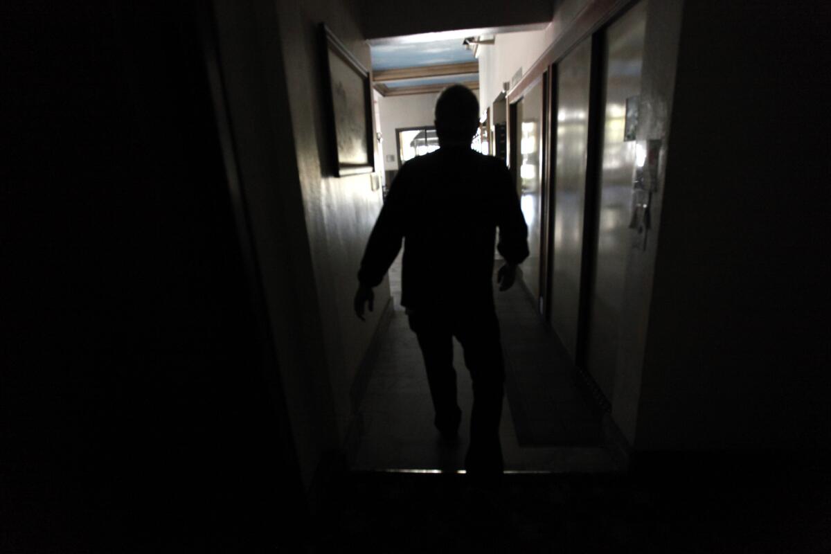 Peter DeBruyn, 70, walks down a hallway Friday at the Sovereign apartments, which were left in the dark by the power outage in Long Beach.
