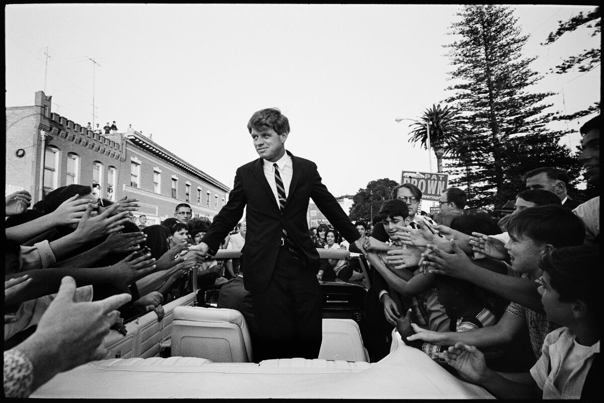 A man in a suit and tie shakes people's hands.