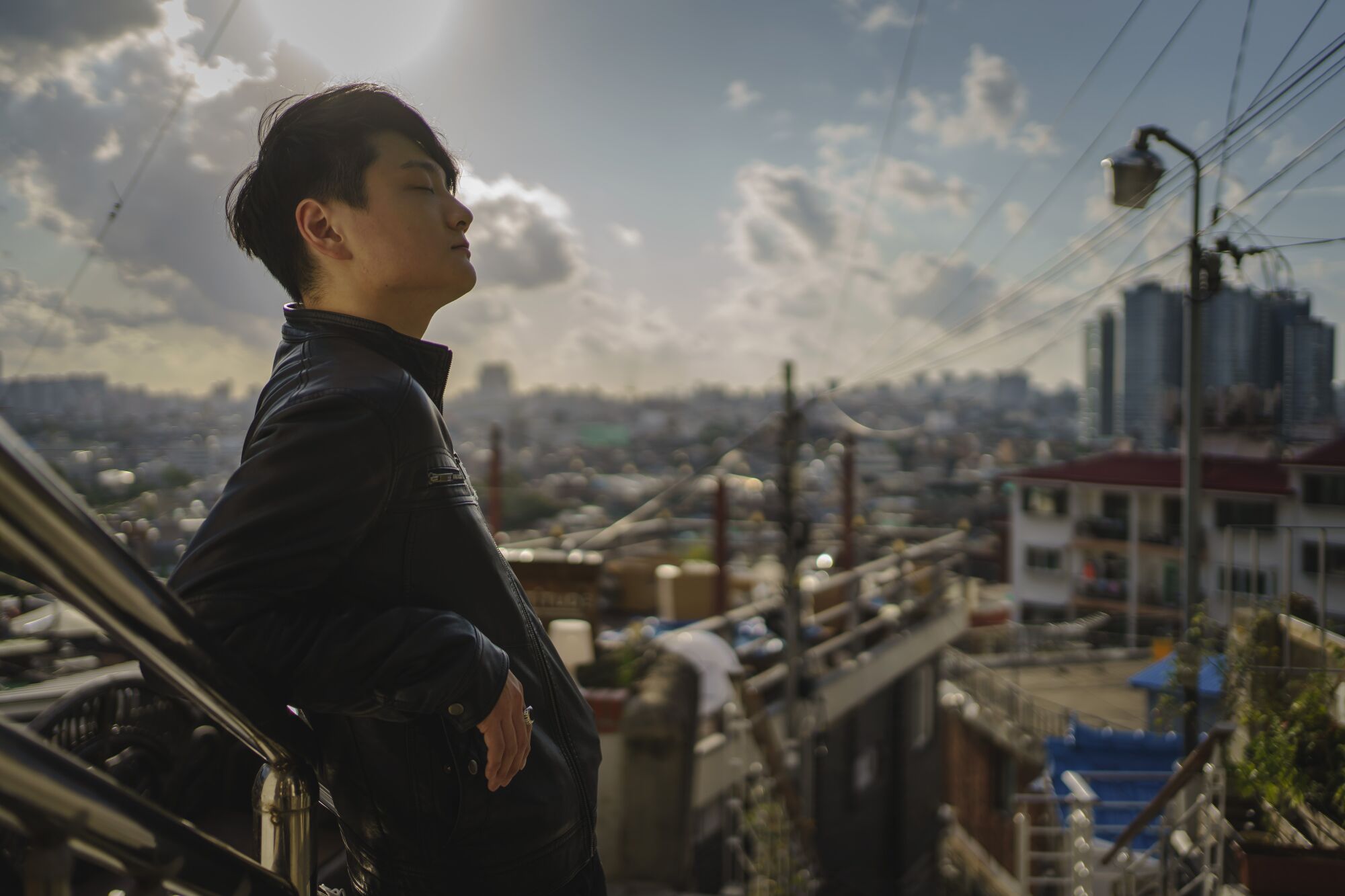 Magician Ed Kwon, 24, poses for a portrait in Seoul, South Korea, on a staircase with the city laid out in the background. 