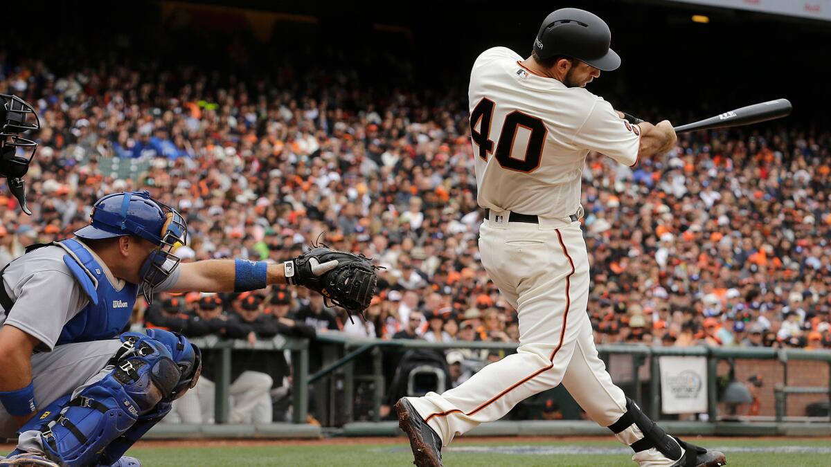 Madison Bumgarner hits a solo home run in front of Dodgers catcher A.J. Ellis on April 9.