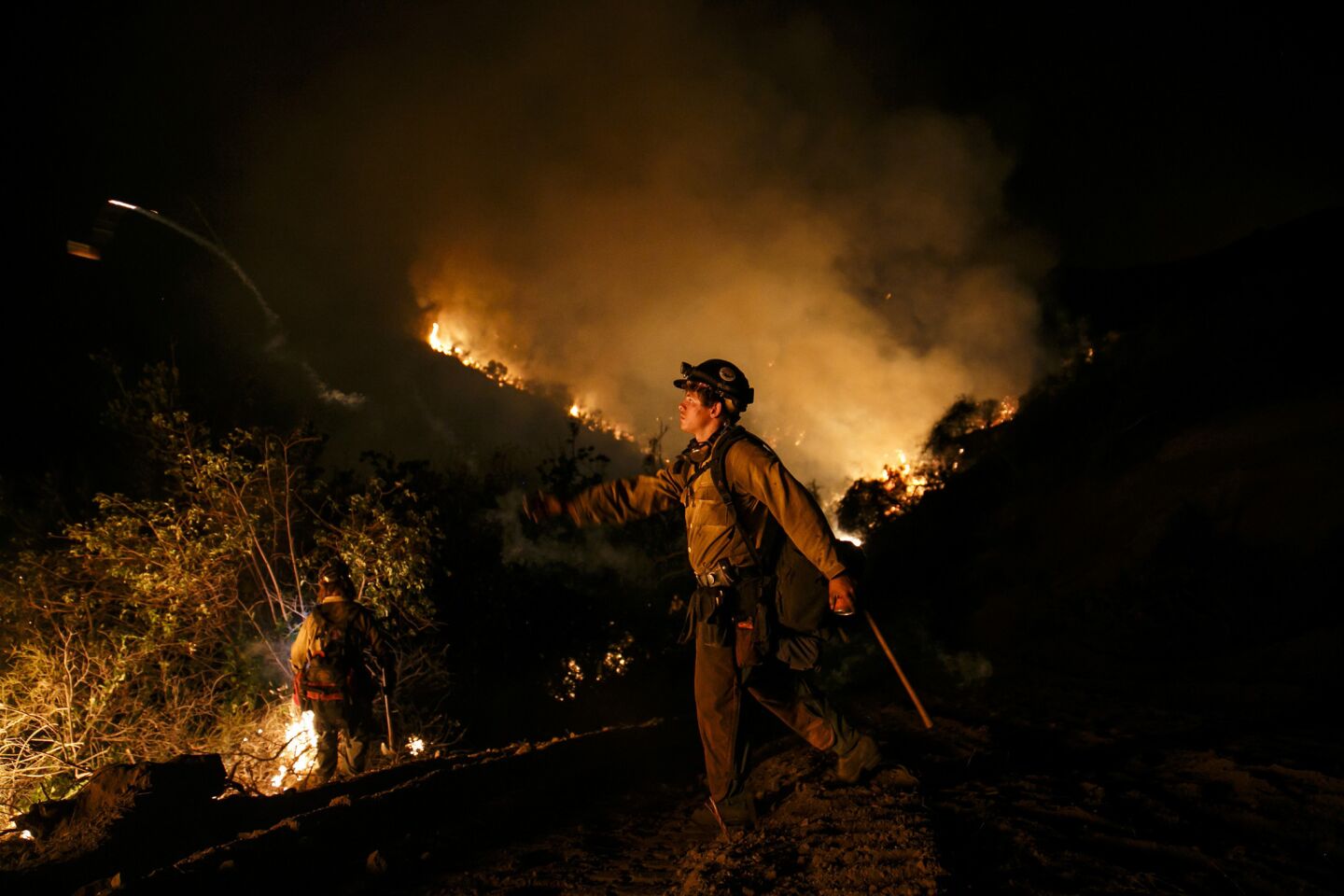 A firefighter torches the dry foliage during a burn-out operation in El Capitan Canyon.