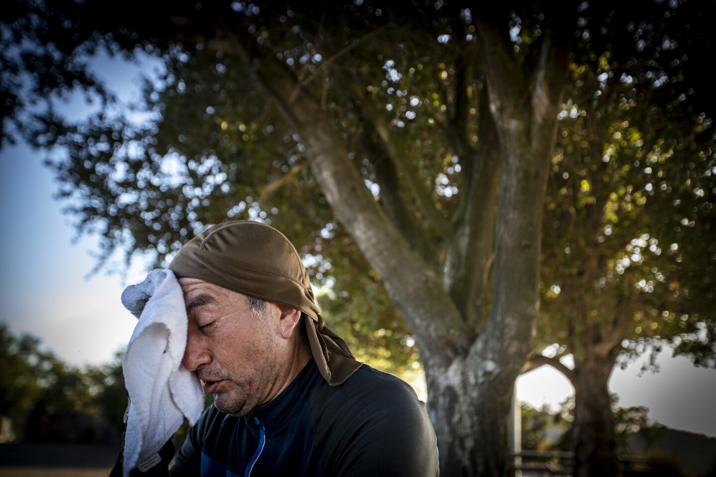 Mountain biker Guillermo Salazar of Reseda wipes sweat from his forehead while taking a break from riding amid temperatures in the 90s at San Vicente Mountain Park in Los Angeles.