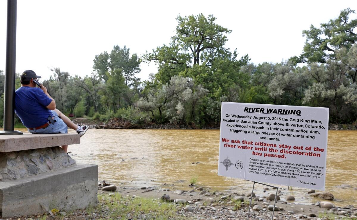 A warning sign from the city is displayed in front of the Animas River as orange sludge from the spill at the Gold King mine upstream flows past Berg Park in Farmington, N.M. on Aug. 8.