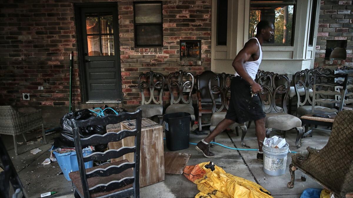 Charles Lewis walks past damaged furniture drying in the carport of his home in Kingwood, a suburb north of Houston.