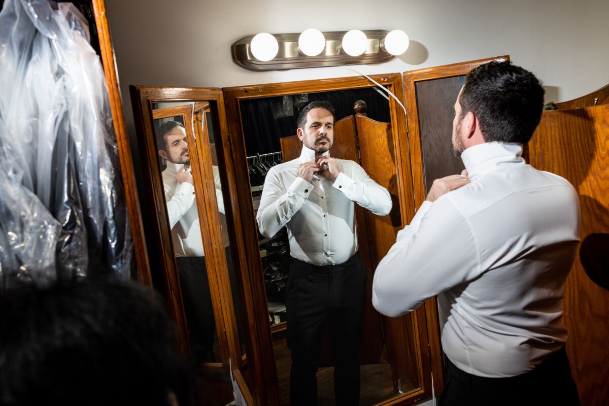 A man tries on a shirt in front of a mirror.
