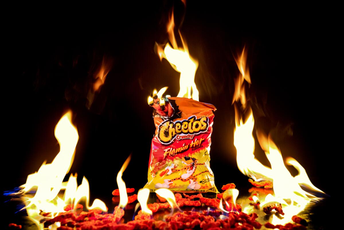 A bag of Cheetos Crunchy Flamin' Hot flavor, surrounded by and catching on fire.