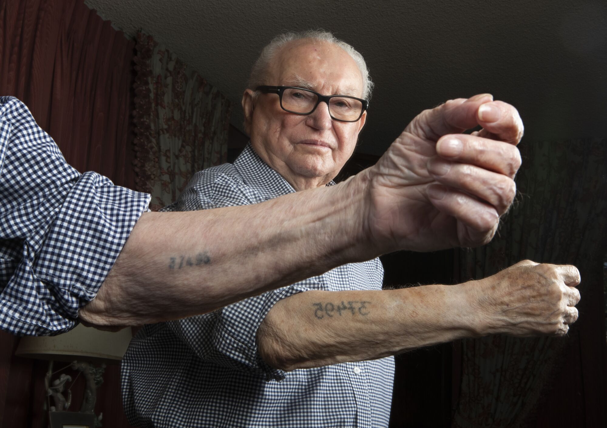 Hakman shows his prisoner number tattooed on both sides of his left arm. He received the smaller one, in the foreground, when he first arrived at Auschwitz in 1942, and the larger one the next day at Birkenau.