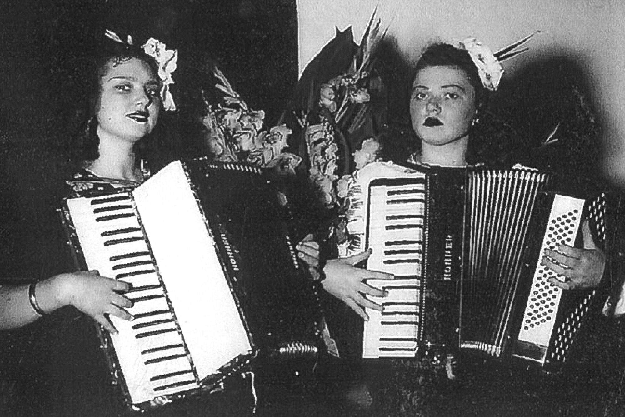 A black-and-white photo of two young women playing accordions.