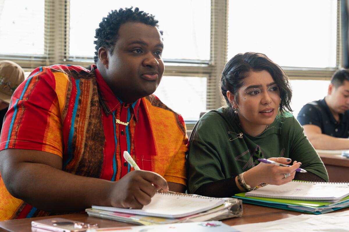 Male and female high school students at a table with notebooks in front of them