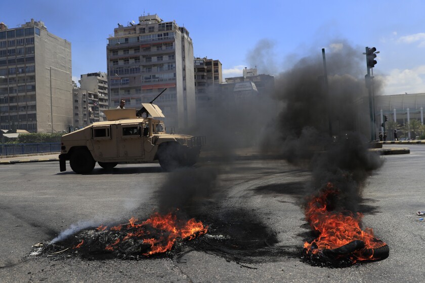 A Lebanese army humvee passes next of burned tires that set on fire by protesters to block a main highway, during a protest against the increase in prices of consumer goods and the crash of the local currency, in Beirut, Lebanon, Thursday, June 17, 2021. Shops, government offices, businesses and banks shut their doors Thursday in response to a call for a general strike by Lebanon's main labor union. (AP Photo/Hussein Malla)