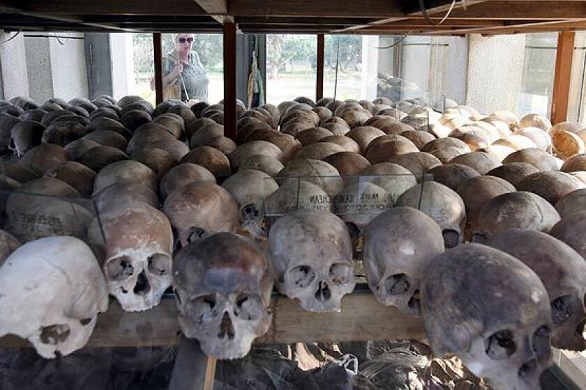 A foreign tourist views skulls of Khmer Rouge victims on display at Choeung Ek Genocidal Center outside Phnom Penh, Cambodia. A United Nations-backed tribunal this week will put the first of five former Khmer Rouge leaders before a panel of Cambodian and international judges on charges of crimes against humanity.