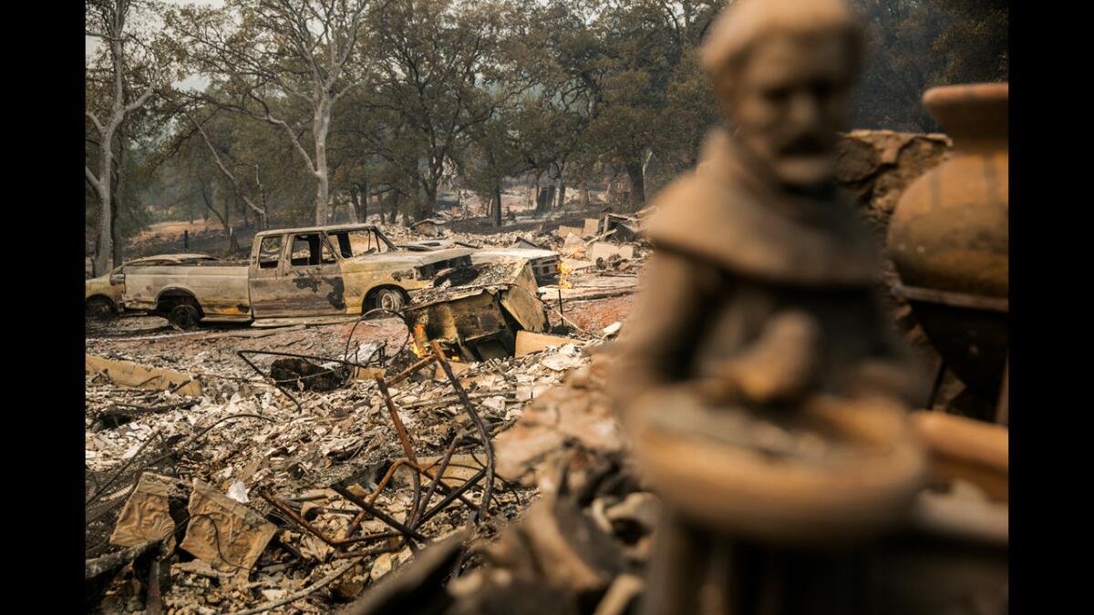 A statue sits in the foreground of burned down homes in the residential community of Hidden Valley Lakes, near Middletown, on Sunday.
