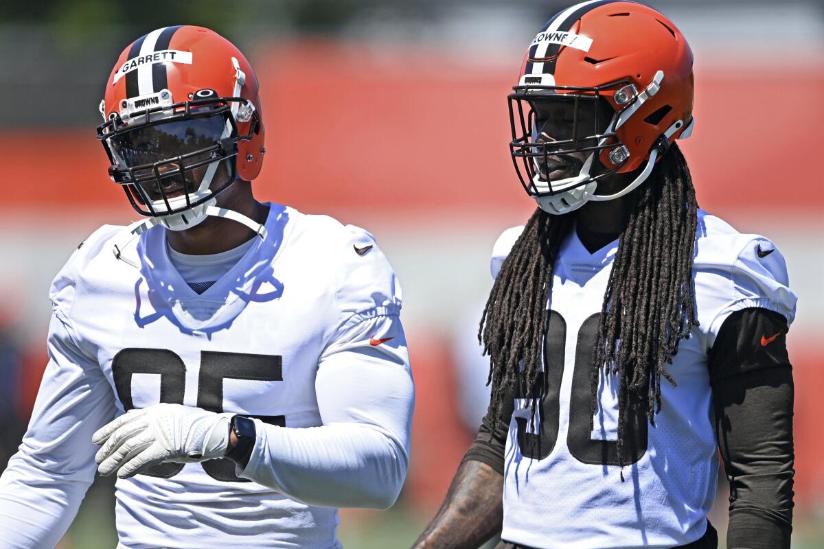 FILE - In this June 17, 2021, file photo, Cleveland Browns defensive linemen Jadeveon Clowney, right, and Myles Garrett watch during NFL football practice in Berea, Ohio. he Browns will have at least seven new starters on defense — maybe more depending on the package they're in — when the season kicks off Sunday against the Kansas City Chiefs at Arrowhead. (AP Photo/David Dermer, File)