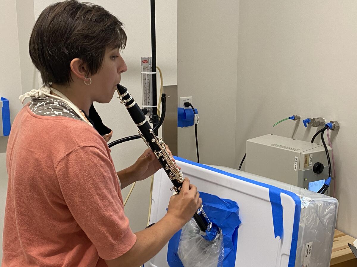 La investigadora Tehya Stockman toca un clarinete para medir la producción de pulverizaciones.