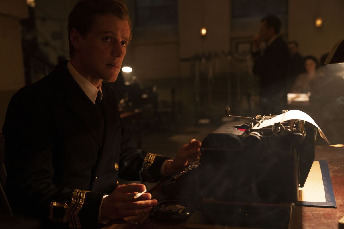 A British military officer smokes a cigarette while sitting at a typewriter in the movie "Operation Mincemeat"