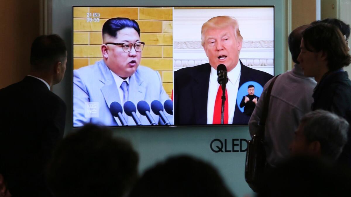 People watch a TV screen showing file footage of North Korean leader Kim Jong Un and President Trump during a news program at the Seoul Railway Station in Seoul.