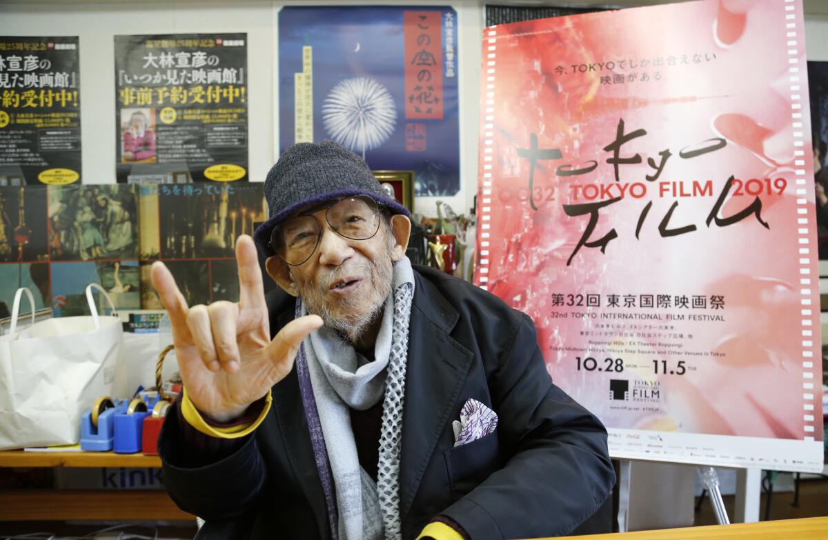 Fotografía de archivo del 11 de octubre de 2019 del director japonés Nobuhiko Obayashi haciendo la señal de “Te amo” para enfatizar que es un mensaje importante en sus películas, durante una entrevista en su estudio en Tokio. (AP Foto/Yuri Kageyama, Archivo)