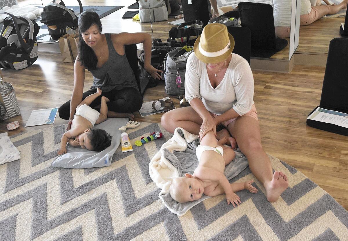 Harmony Clemente massages the leg of her 8-month-old son, Bronson, as she follows the lead of massage class leader Paula Curtiss at The Dailey Method above Spa Gregorie’s in Newport Beach.