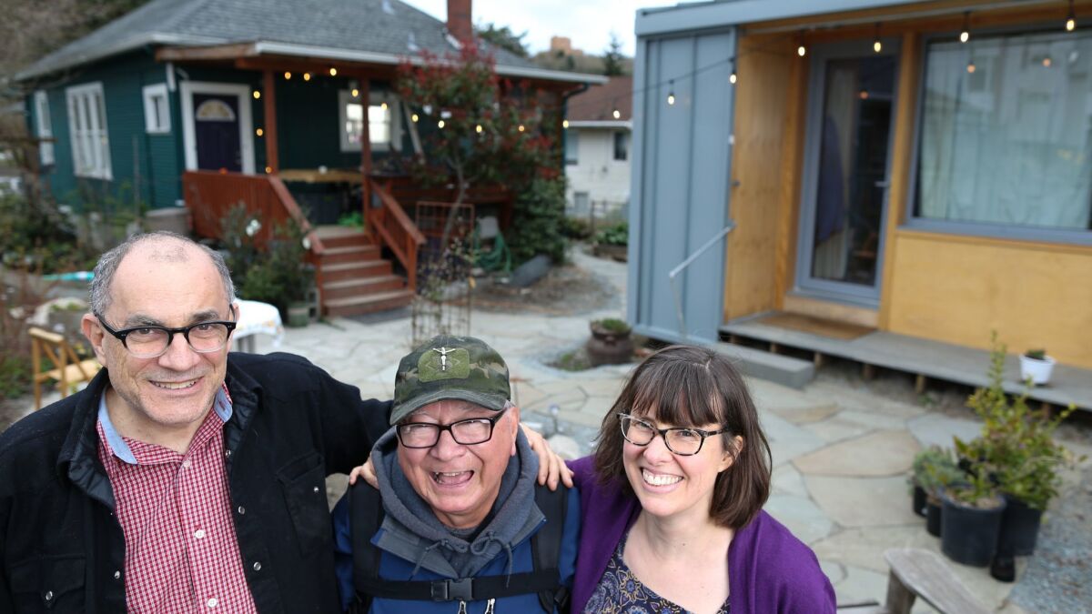Dan Tenenbaum, left, and Kim Sherman, right, with Robert Desjarlais, a formerly homeless man who lives in a 125-square-foot house in their Seattle backyard.