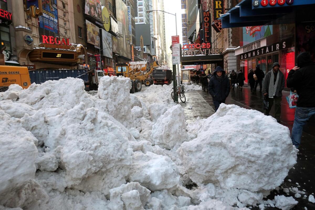 Department of Sanitation workers use bulldozers to clean snow from a street in Times Square in New York early Monday.