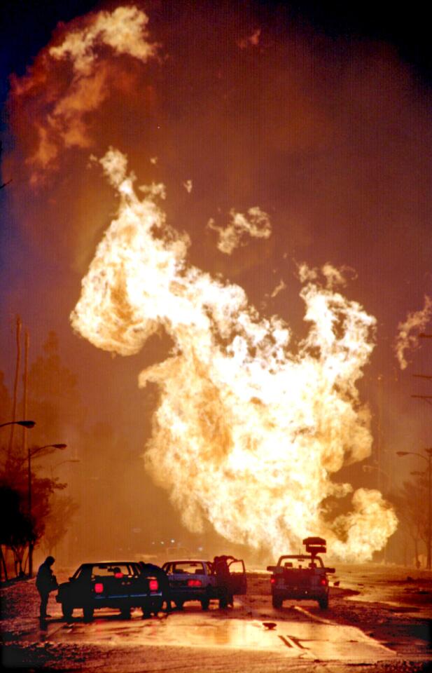 Cars are dwarfed by a wall of flames that was created when a natural gas line ruptured in the earthquake.