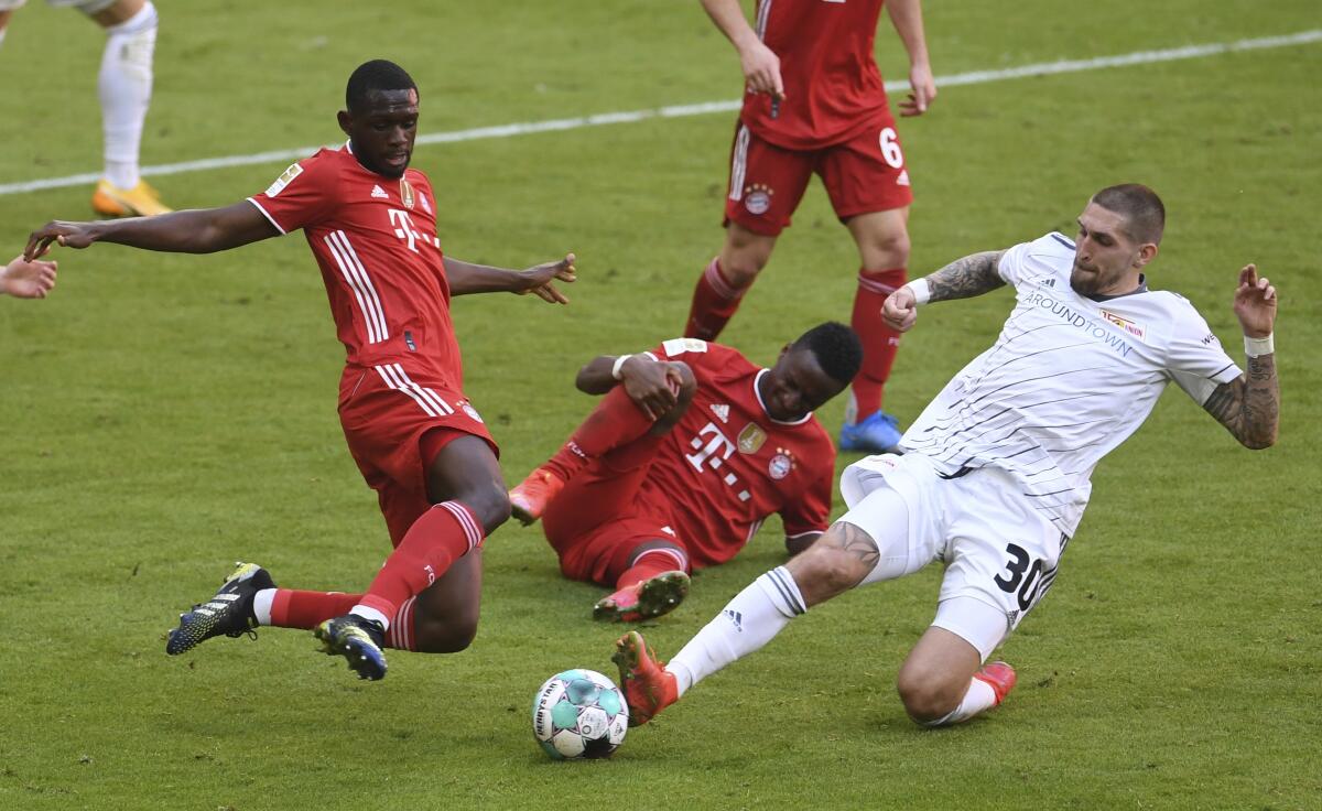 Bayern's Tanguy Nianzou, left, and Union's Robert Andrich challenge for the ball during the German Bundesliga soccer match between Bayern Munich and FC Union Berlin at Allianz Arena in Munich, Germany, Saturday, April 10, 2021.(Andreas Gebert/Pool via AP)