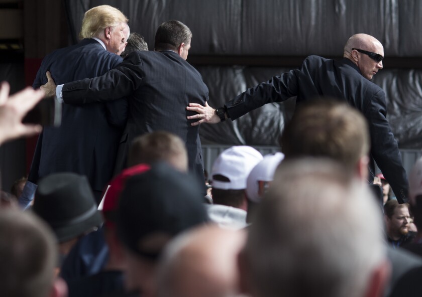 Secret Service agents swarm around Republican presidential candidate Donald Trump after a protester tried to rush the stage at a rally Saturday in Vandalia, Ohio.