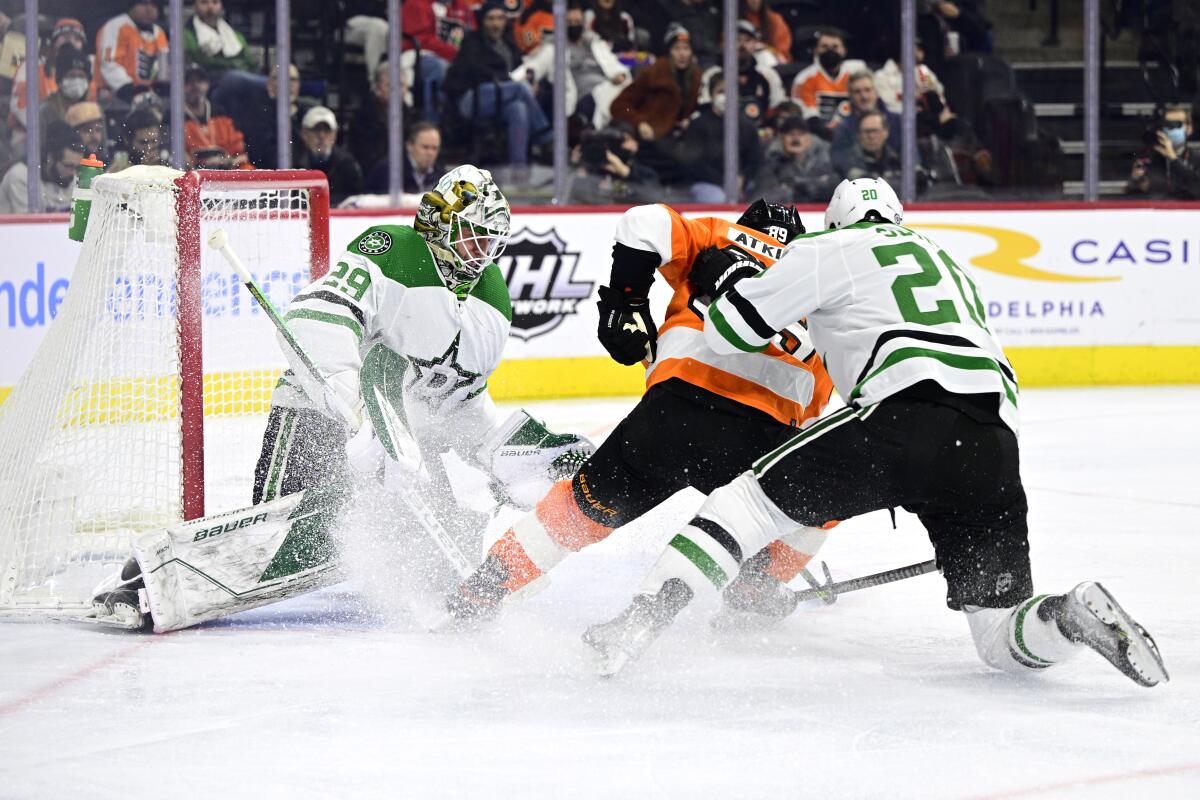 Dallas Stars goaltender Jake Oettinger, left, makes a save on a shot by Philadelphia Flyers' Cam Atkinson, center, as Ryan Suter (20) defends during the second period of an NHL hockey game, Monday, Jan. 24, 2022, in Philadelphia. (AP Photo/Derik Hamilton)
