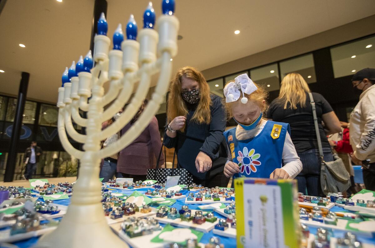 Emily Cary and her mother, Katie Cary, from Girl Scout Troop 9649 look at handmade menorahs.
