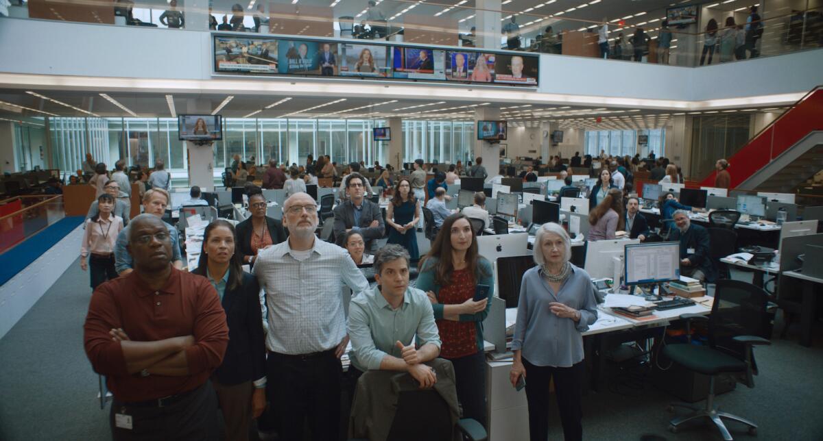Dozens of people watch TV monitors in a newsroom in the movie "She Said."
