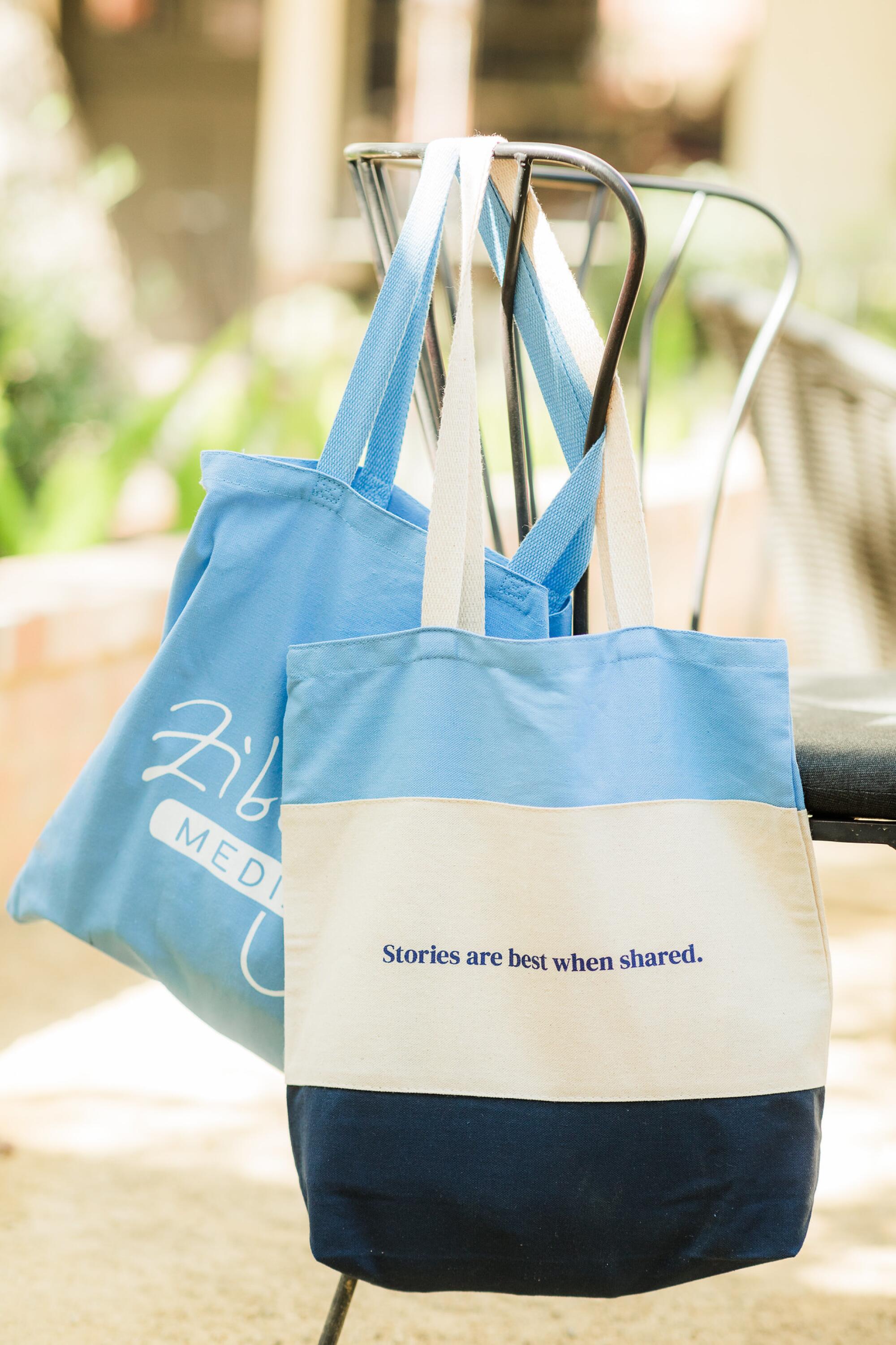 Two Zibby Media tote bags hang from the back of a chair