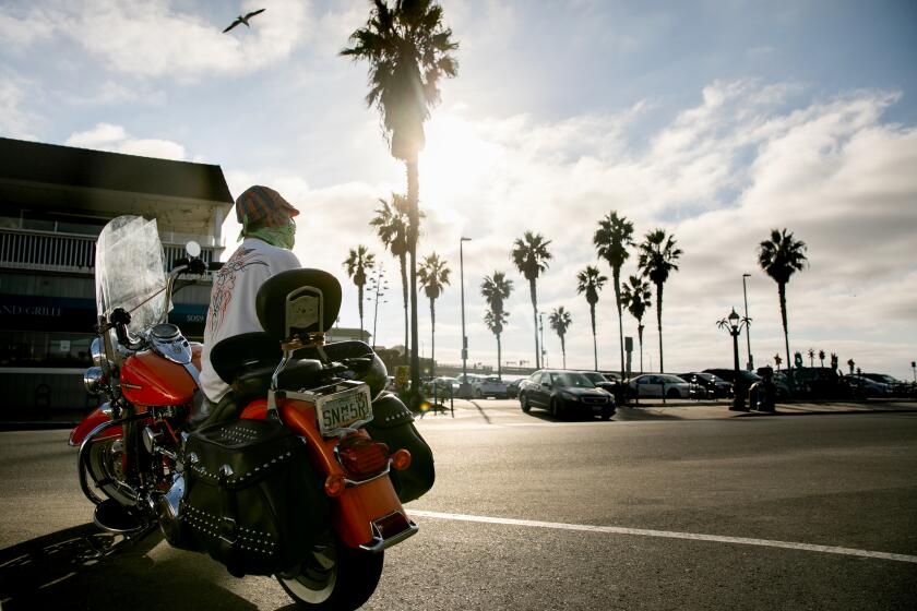 SAN DIEGO, CA - OCTOBER 19: Greg Deyesso dons a face mask and a bandana while sitting on his Harley Davidson motorcycle in the Ocean Beach neighborhood on Monday, Oct. 19, 2020 in San Diego, CA. Deyesso, a Clairemont resident who visits the same spot in Ocean Beach every day, said he sees a lot of people not taking the virus seriously enough. OItOs really sad that a majority of the people down here do not wear a mask,O he said. (Sam Hodgson / The San Diego Union-Tribune)