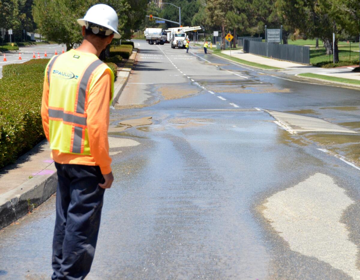A Paulus crew employee checks out the buckling on San Joaquin Hills Road from a broken water pipe.