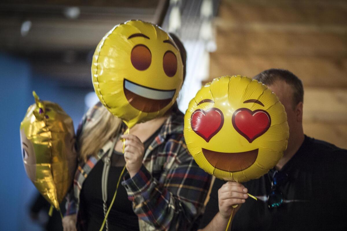 Attendees at the Emojicon launch party pose for pictures with emoji balloons.