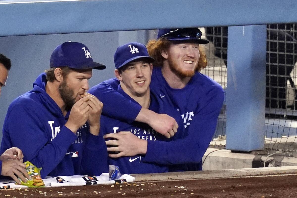 Dodgers pitchers Clayton Kershaw, Walker Buehler and Dustin May joke around in the dugout during a game.
