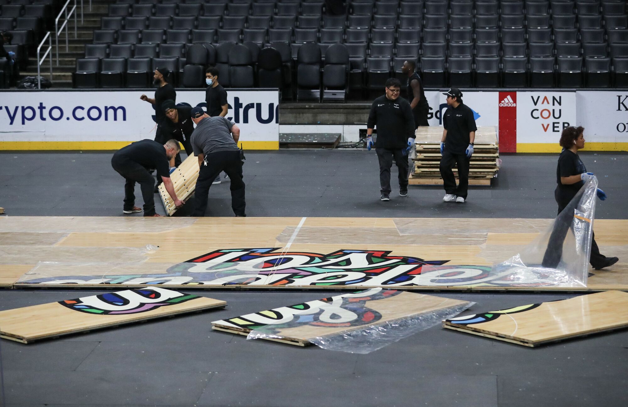 Les employés changent les surfaces de jeu de Crypto.com Arena du bois dur après un match des Clippers de l'après-midi à la glace.