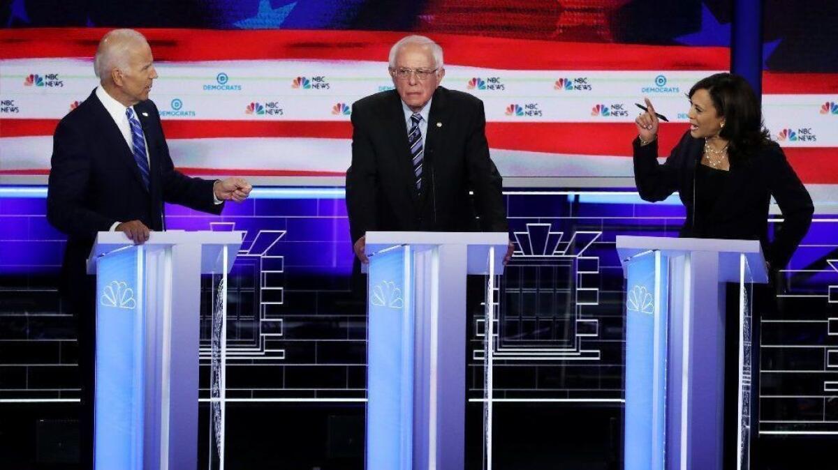 Sen. Kamala Harris, right, and former Vice President Joe Biden, left, speak as Sen. Bernie Sanders looks on during the second night of Democratic presidential debate on June 27.