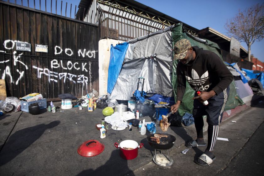 LOS ANGELES, CA - NOVEMBER 26: During the global coronavirus pandemic Anthony Curry, 52, is cooking outside his tent in the skid row area on Thanksgiving Thursday, Nov. 26, 2020 in Los Angeles, CA. He says living out here is "economic purgatory." The number of people living on the sidewalks in Los Angeles is growing during the pandemic. (Francine Orr / Los Angeles Times)