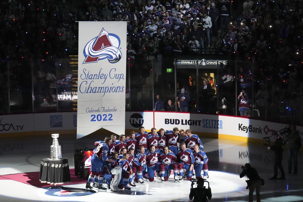 Members of the Colorado Avalanche pose for a photo as their Stanley Cup championship banner is raised.