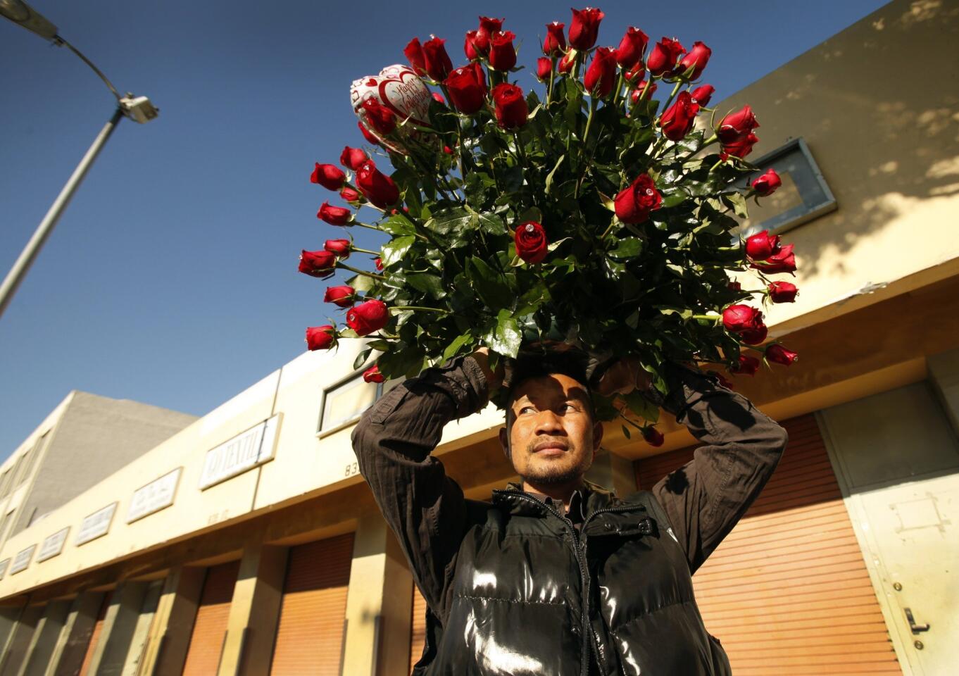 Chiv Mer holds a giant bouquet of roses on his head as he waits for his friend to open the back door of a van that will hold the flowers he has purchased for a secret admirer in the flower district of downtown Los Angeles on Valentine's Day.